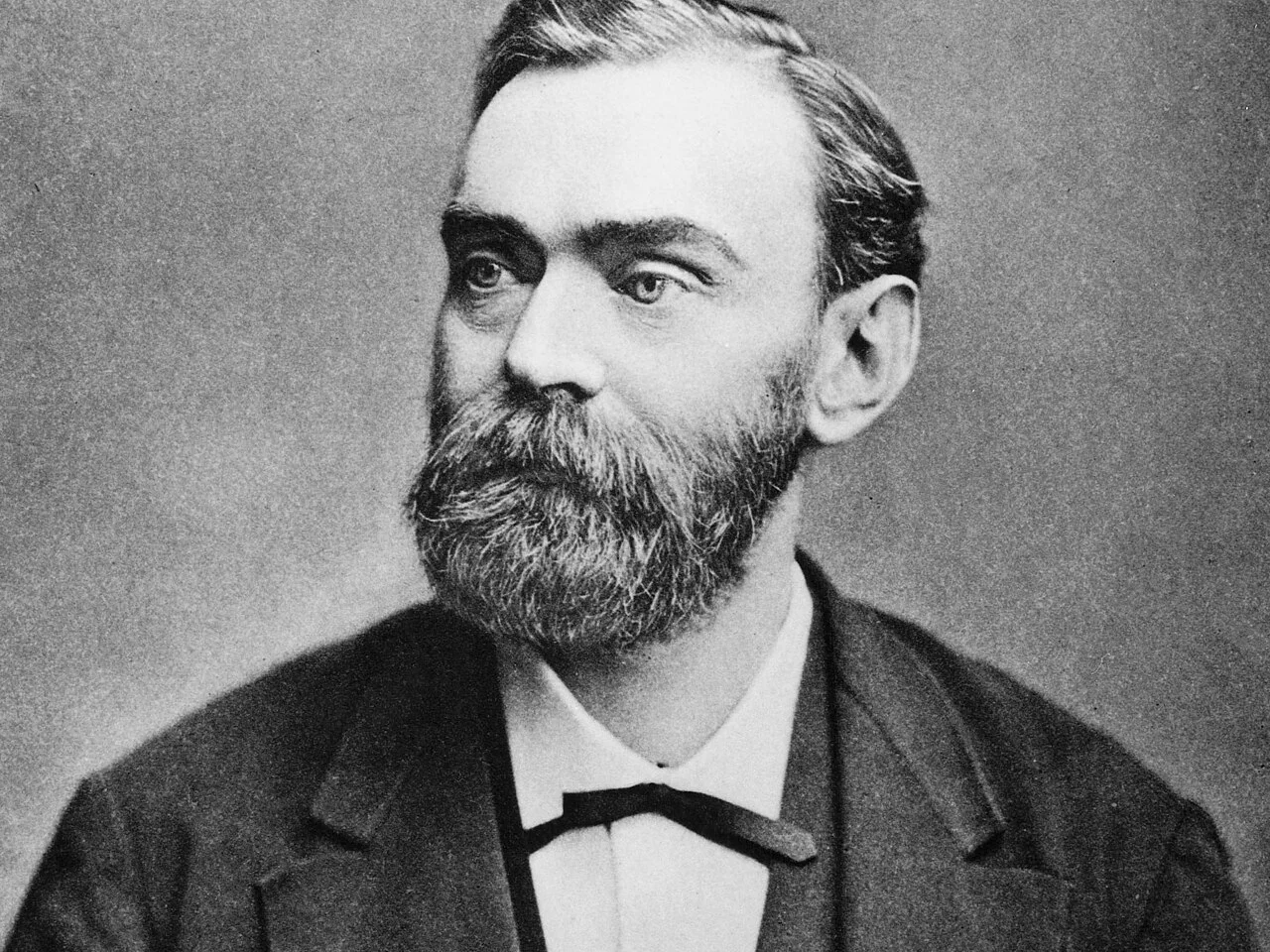 Alfred Nobel med helskägg, mörk kavaj och fluga, svartvitt porträttfoto från 1800-talet